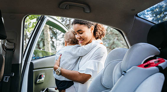 mother putting baby daughter in a car seat