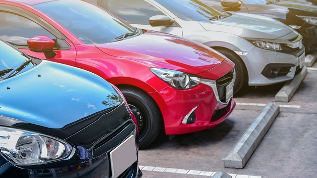 A row of cars parked side-by-side in a parking lot.