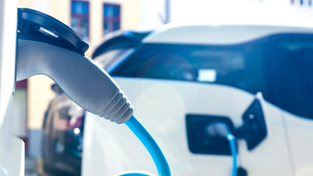 Side view of an electric vehicle charging cable plugged into a car.