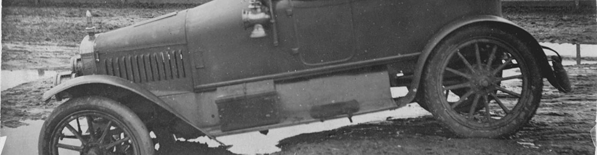 1920s parramatta road car stuck in mud bw 1920s black and white photograph of a vintage car with its front wheels stuck in a muddy puddle on a dirt road