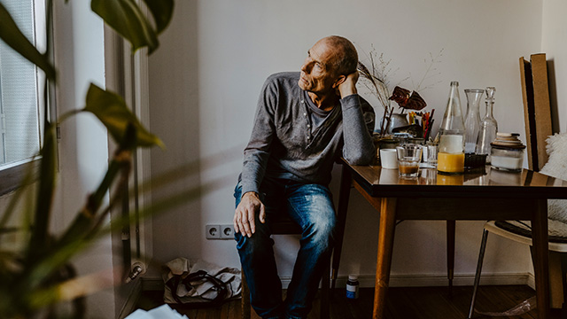An older man sits alone at a table