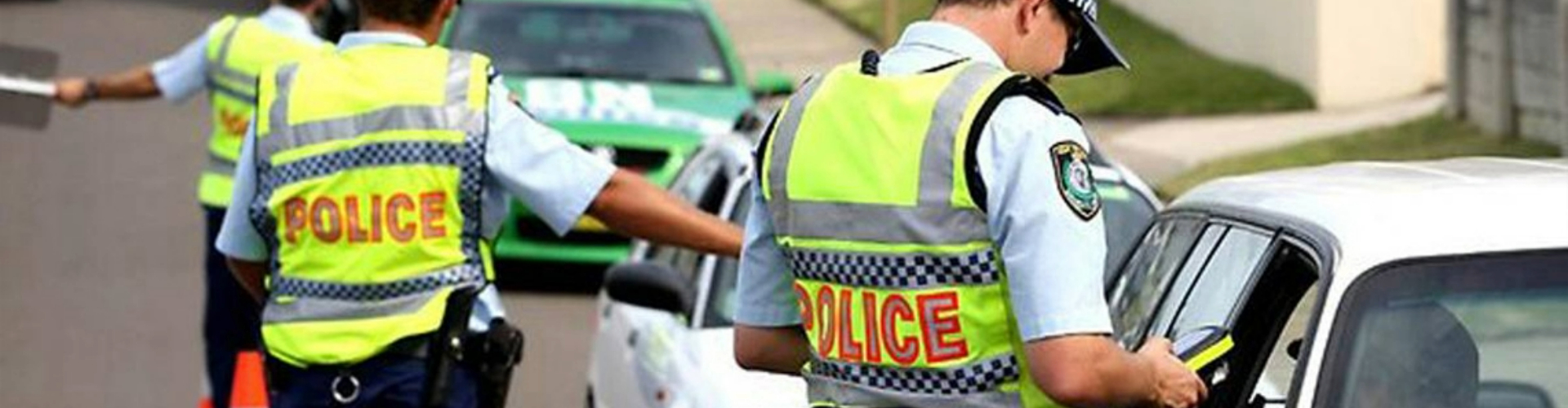 Police officers stopping a line of cars for random breath testing on a sunny day.