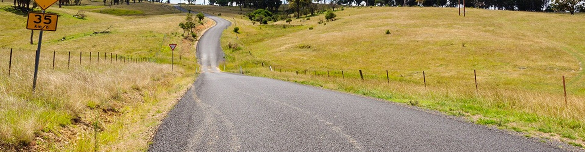 A winding country road with tire marks on it