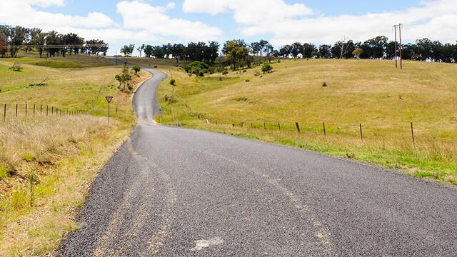 A winding country road with tire marks on it