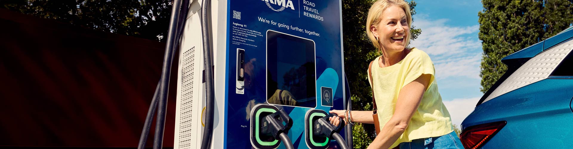 A woman in yellow shirt charging at an NRMA EV charger