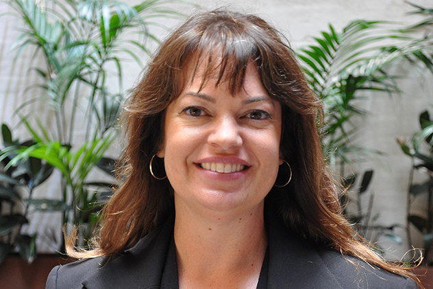 A woman with brown hair in font of pot plants