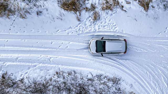 Drone shot of a car driving in snow