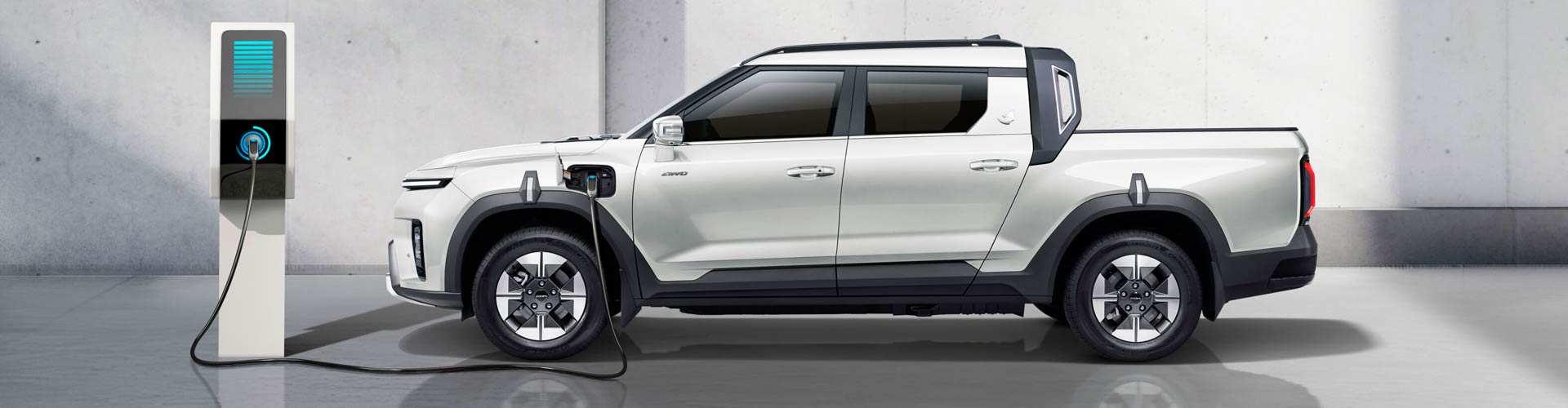 A white electric ute charging against a white wall