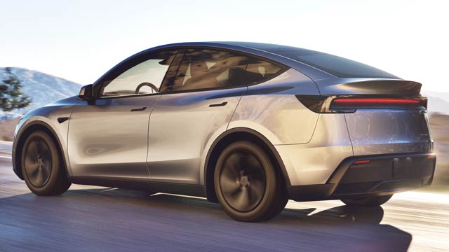 Silver Tesla Model Y seen from rear angle driving on mountain road