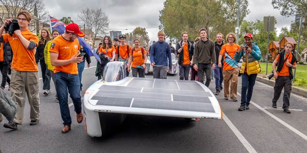 ANU Solar Racing Team solar car team wearing orange shirts at Australia solar powered car race event.