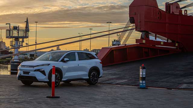 A car rolls off a cargo ship at sunset