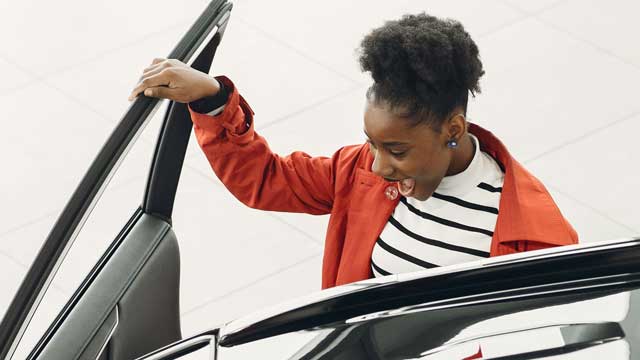 A woman in red jacket open car door with excitement