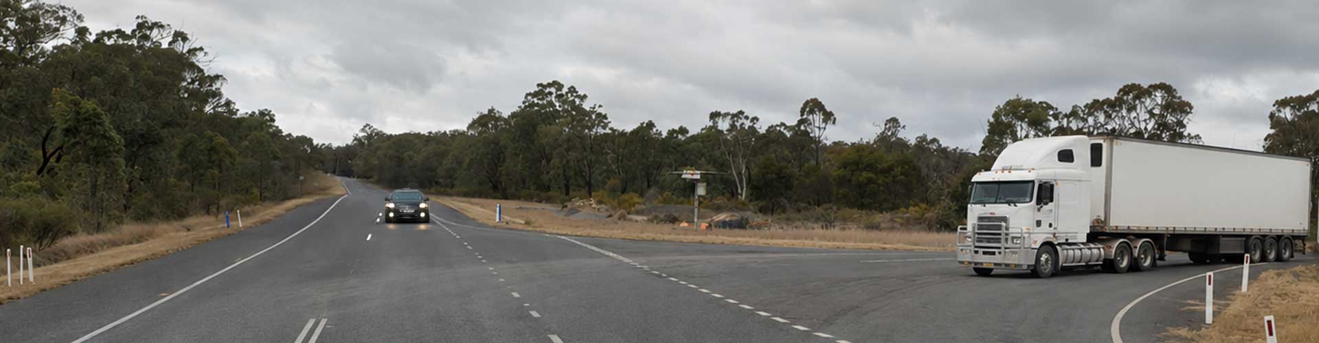 A car approaches an intersection while a truck waits