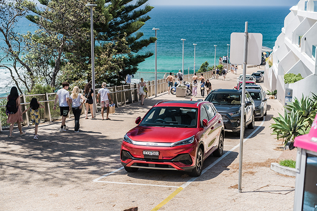 A red BYD Atto 3 parked near the beach