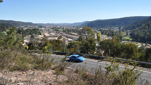 A blue car driving past a country town