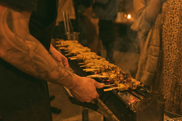 A man cooking kebabs over hot coals