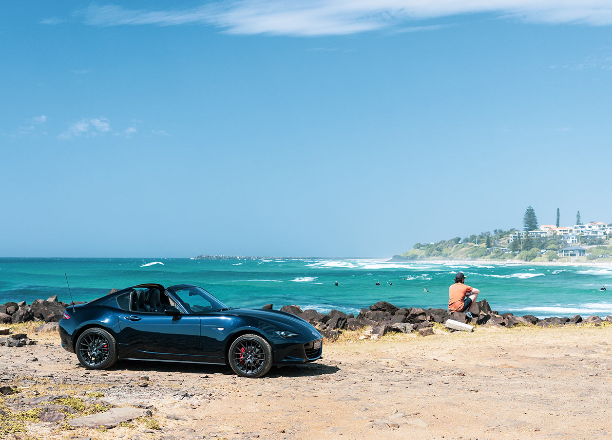 Car and man on a lookout overlooking the beach