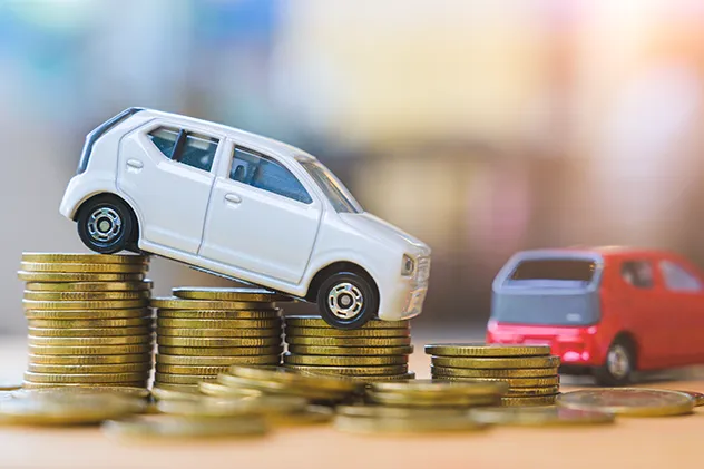 white toy car on a decline on top of gold coins