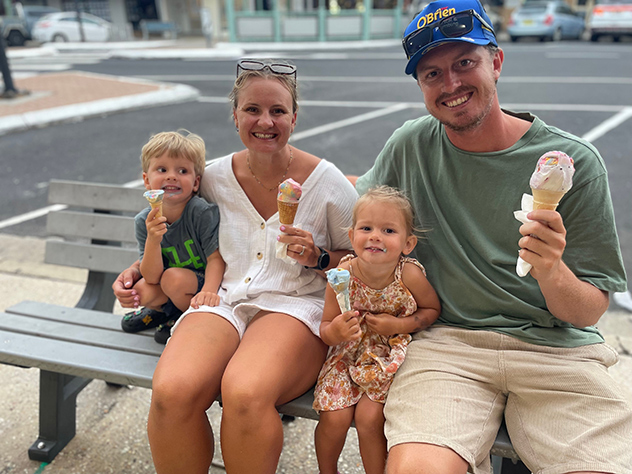 Family of four sitting down on a street bench enjoying ice cream cones