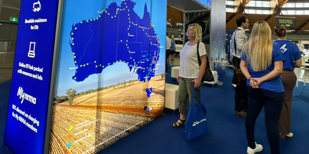 A lady standing beside and looking at a big blue map on a wall.