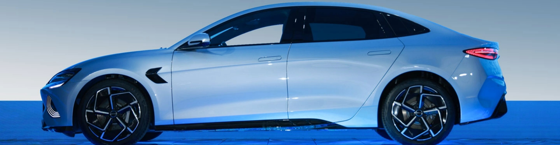 Side view of a light blue 2023 BYD Seal, parked on a dark blue platform.