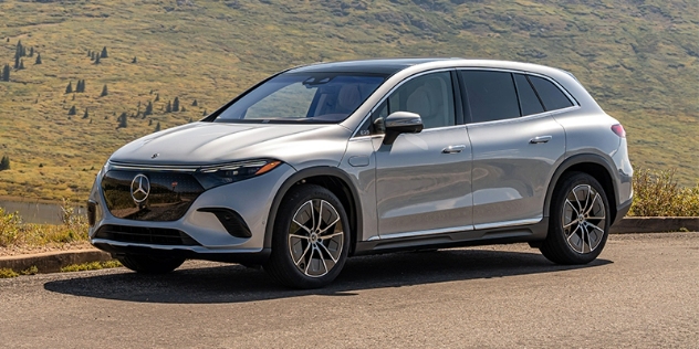 Side view of a Mercedes Benz EQS parked along the edge of a cul-de-sac with a mountainous background.