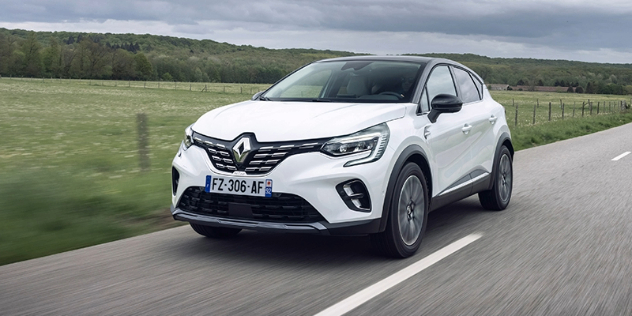 Front view of a white Renault Megane E Tech driving along a road in the countryside.