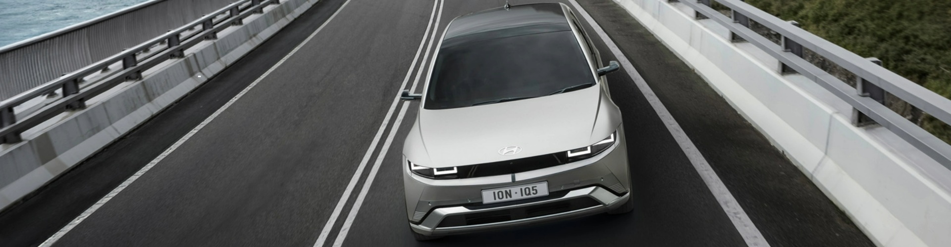 Front view of silver 2025 Hyundai Ioniq 5 driving along a highway.