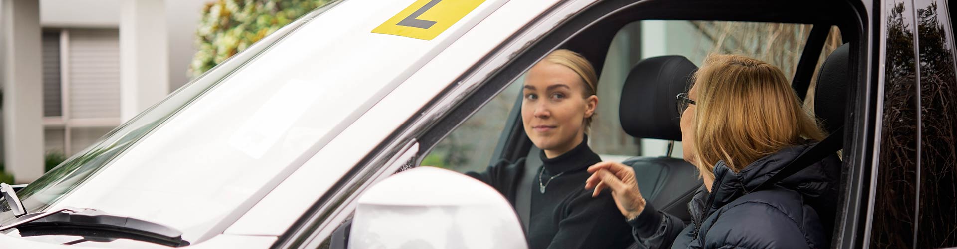A mother and daughter in a car with an L plate on the windscreen