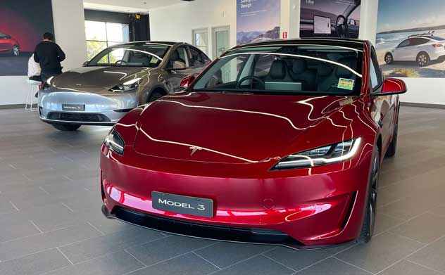 Red 2024 Tesla Model 3 parked in a showroom