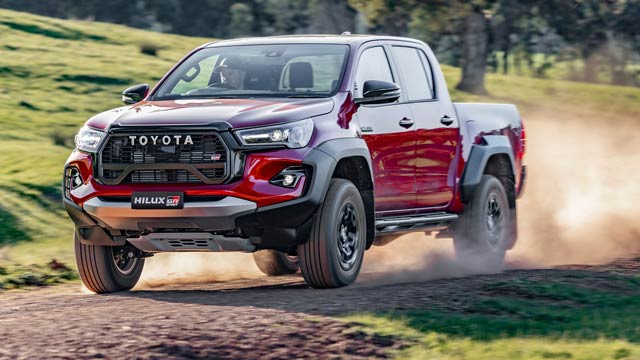 A red 2026 Toyota Hilux with dirt behind