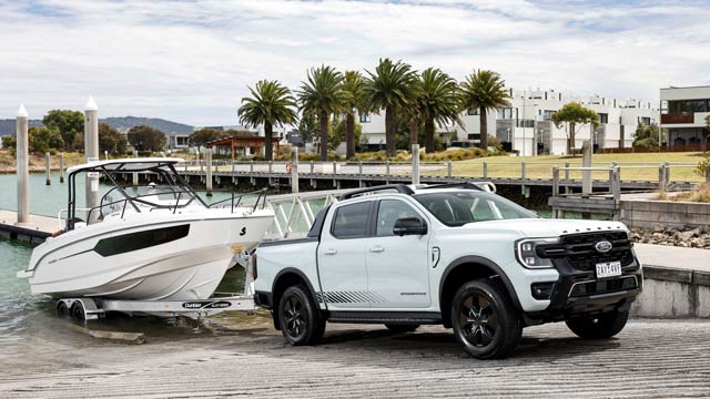 A white Ford Ranger PHEV pulls a boat up a ramp 