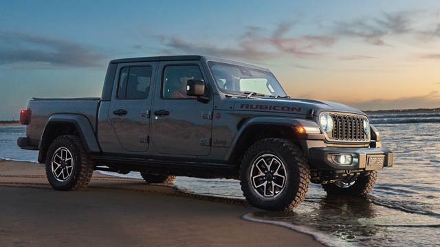 Jeep Wrangler parked on beach with tyres in water