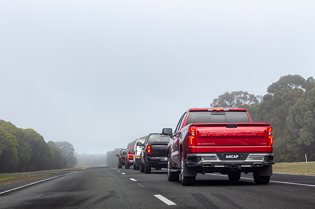 A line of pickup trucks on a foggy road.