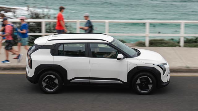 White Kia EV3 driving in front of the beach