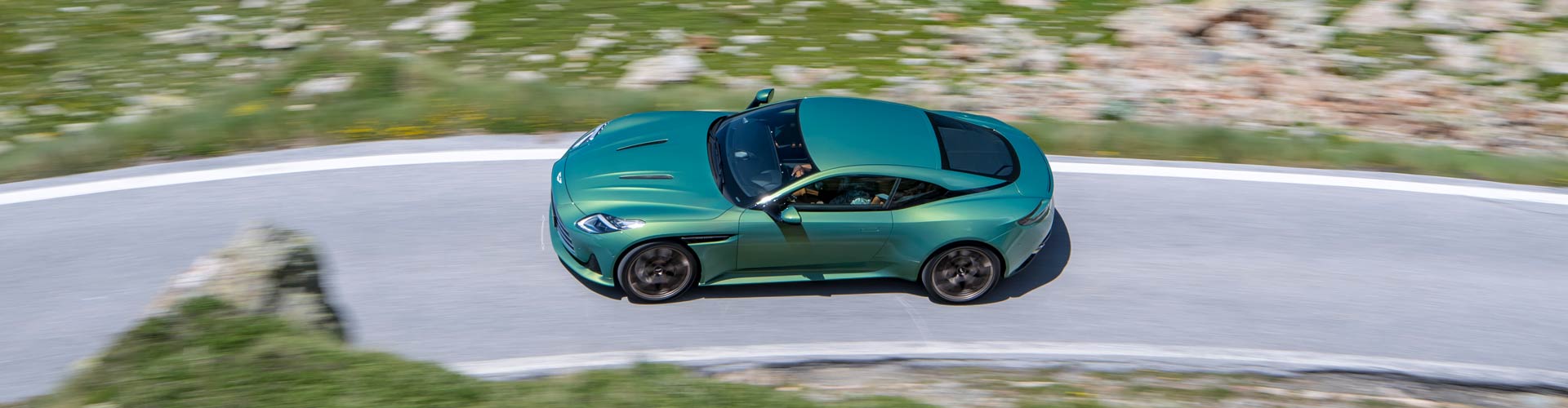 Aerial view of a green 2025 Aston Martin DB12 on a road