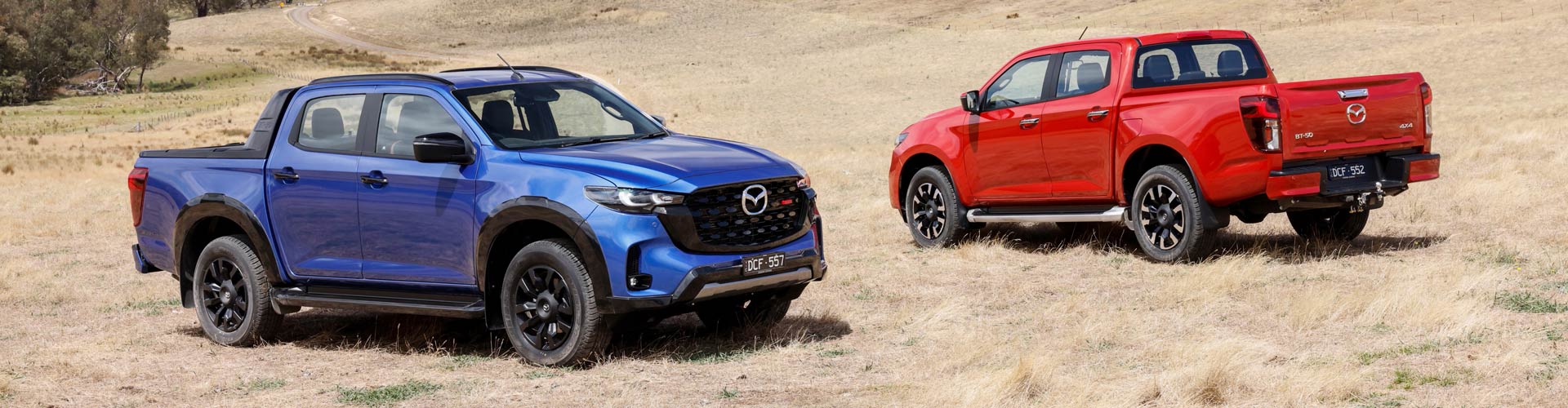 A red and a blue Mazda BT-50 parked on red dirt