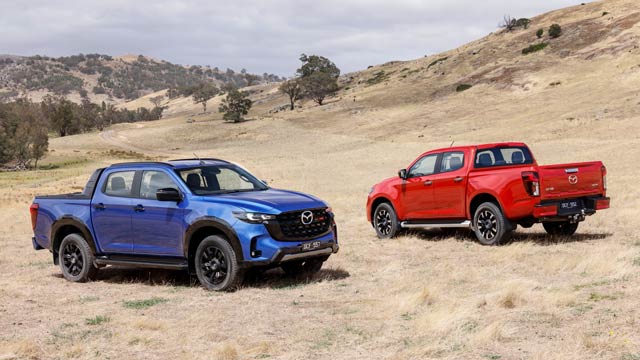 A red and a blue Mazda BT-50 parked on red dirt