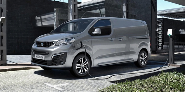 A silver-gray 2024 Peugeot E-Expert in a parking bay plugged into a charging station