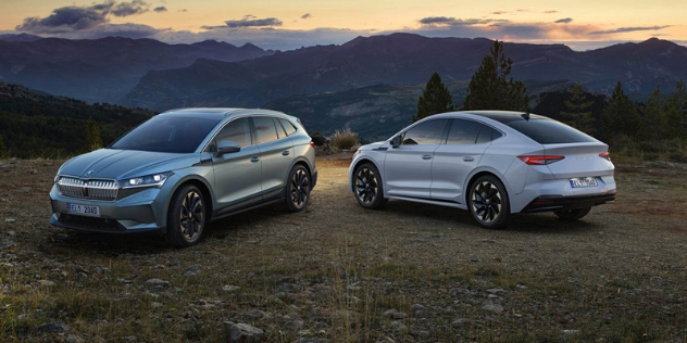 Two 2024 Škoda Enyaqs - an SUV and a coupe - parked in front of a mountain background at dusk