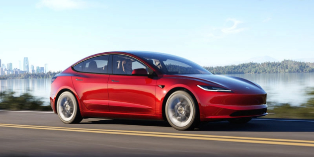 A red 2024 Tesla Model 3 driving on a country road