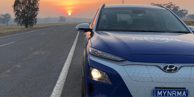 A Hyundai EV with a MYNRMA number-plate and the sun setting in the background 