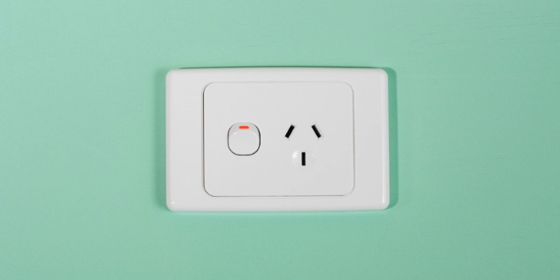 An Australian 240-volt single socket on a pale green wall