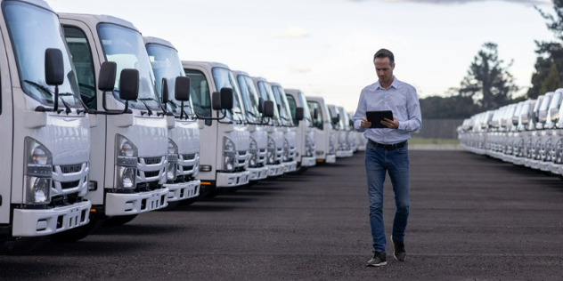 Front view of man walking between two rows of neatly parked trucks.