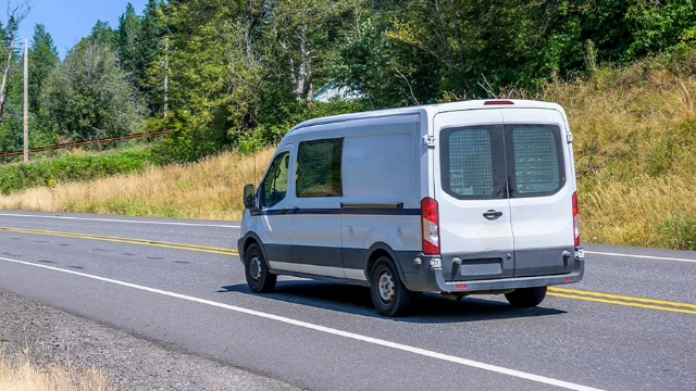 A white fleet vehicle driving along a highway on a sunny day.