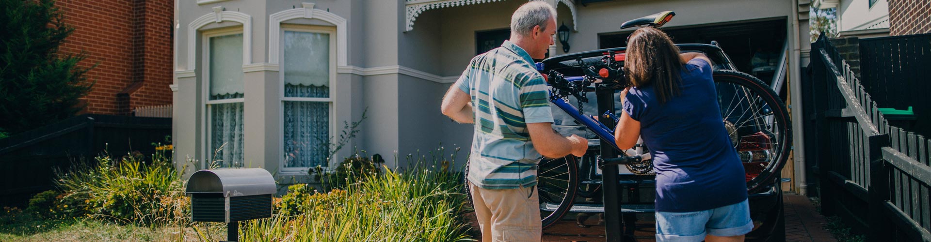 Middle aged couple attaching the family bikes to the bicycle rack on their car, ready for a family bike ride.