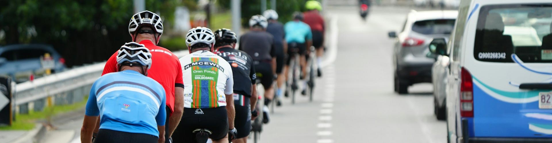 Group of cyclists riding down a road next to cars