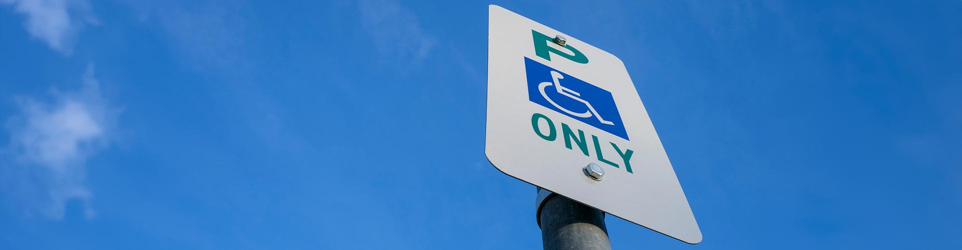 Disabled parking sign against a clear blue sly