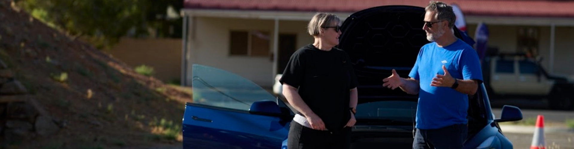 EV Frequently Asked Questions a middle-aged man and woman stand in front of a vehicle with the bonnet up and the man appears to be explaining something