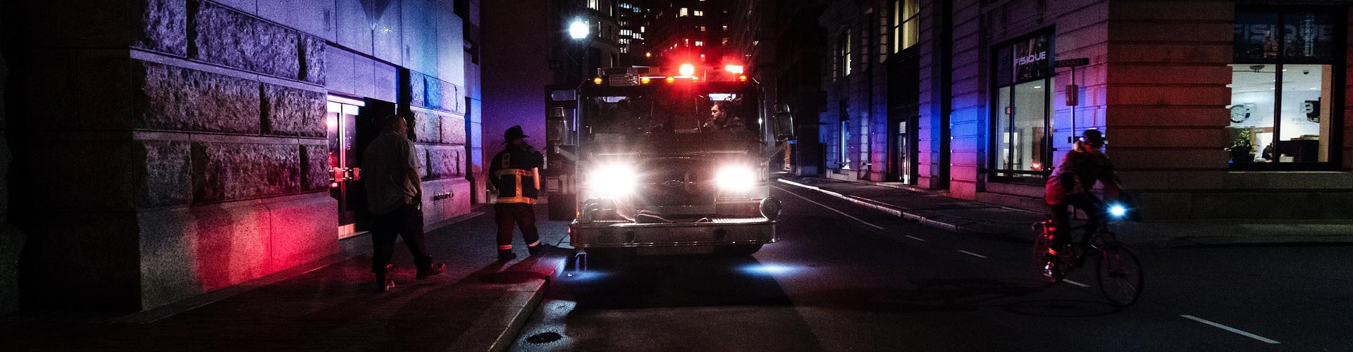 A firetruck parked in a city at night with lights on